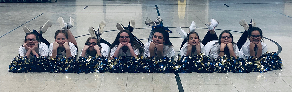 Cheerleaders pose with their pom poms on a gym floor