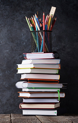 Books stacked together with colored pencils on top